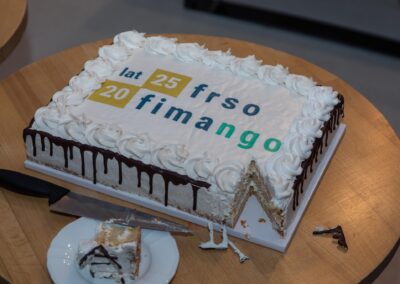 Zdjęcie kolorowe. Na zdjęciu prostokątny jubileuszowy tort z logiem konferencji "25 lat FRSO, 20 lat Fimango". Tort ma wycięty jeden kawałek w kształcie trójkącika.