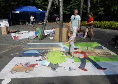 Warsztaty ekologiczne - gigantyczne puzzle na chodniku układający je maluch